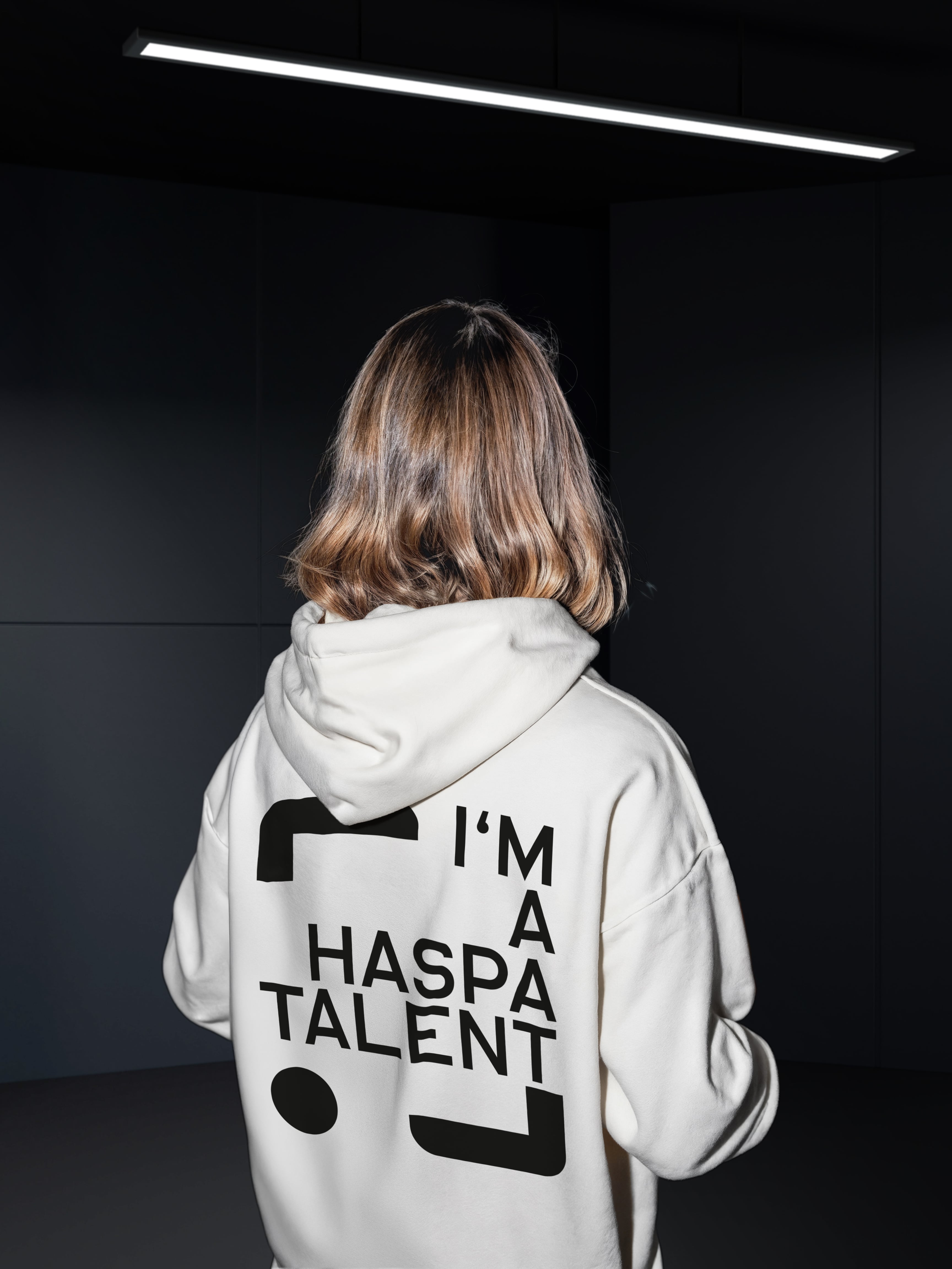 Eine junge Frau wendet der Kamera den Rücken zu. Auf ihrem Pullover ist das Logo der Hamburger Sparkasse zu sehen.