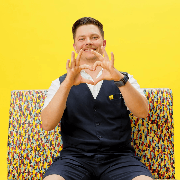 Ein Mann in Berufskleidung der Berliner Verkehrsbetriebe zeigt mit den Händen ein Herz in die Kamera und lächelt.